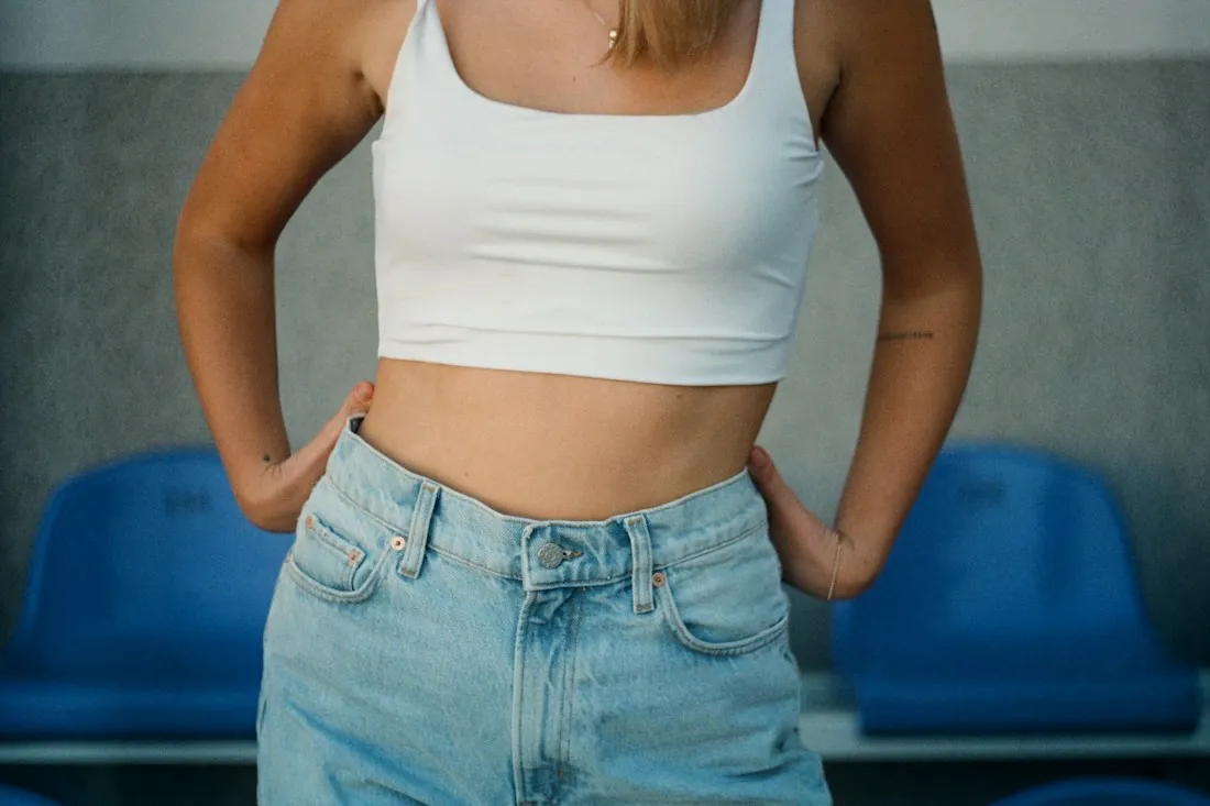 Woman with hands on her waist, in a white top and jeans