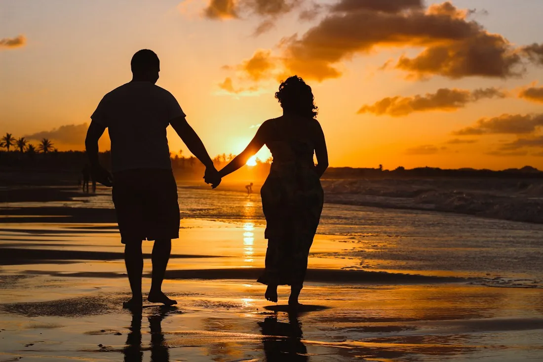 Couple holding hands on a beach at sunset